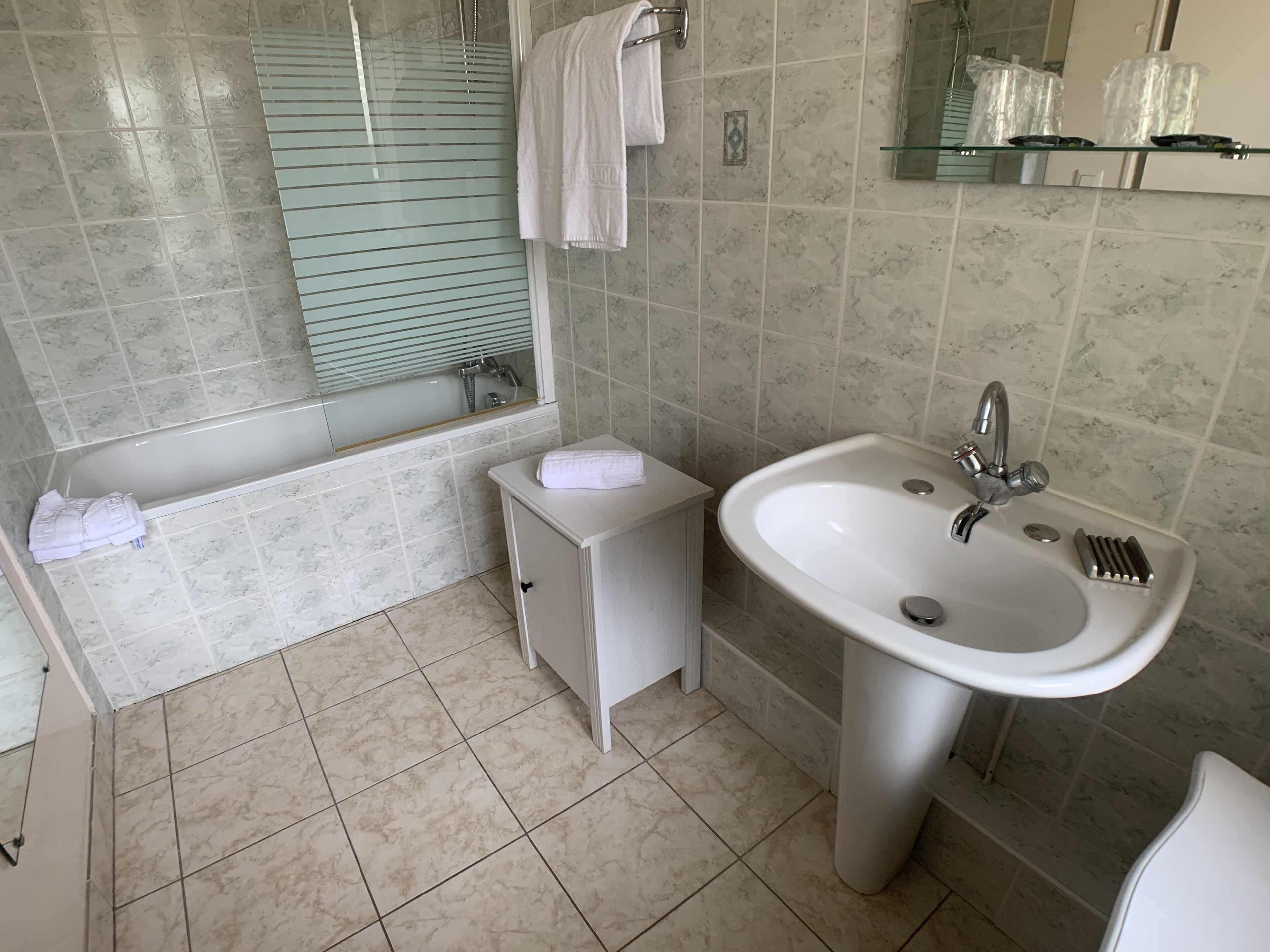 Une salle de bain avec une baignoire, un lavabo et un miroir.