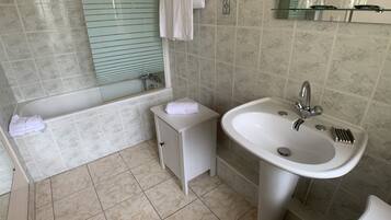 Une salle de bain avec une baignoire, un lavabo et un miroir.