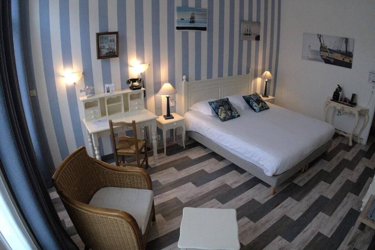 Habitación de hotel con cama, escritorio, silla y una mesita.