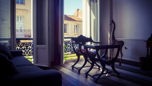 Een kamer met balkon, een tafel, een girafbeeld en een bank.