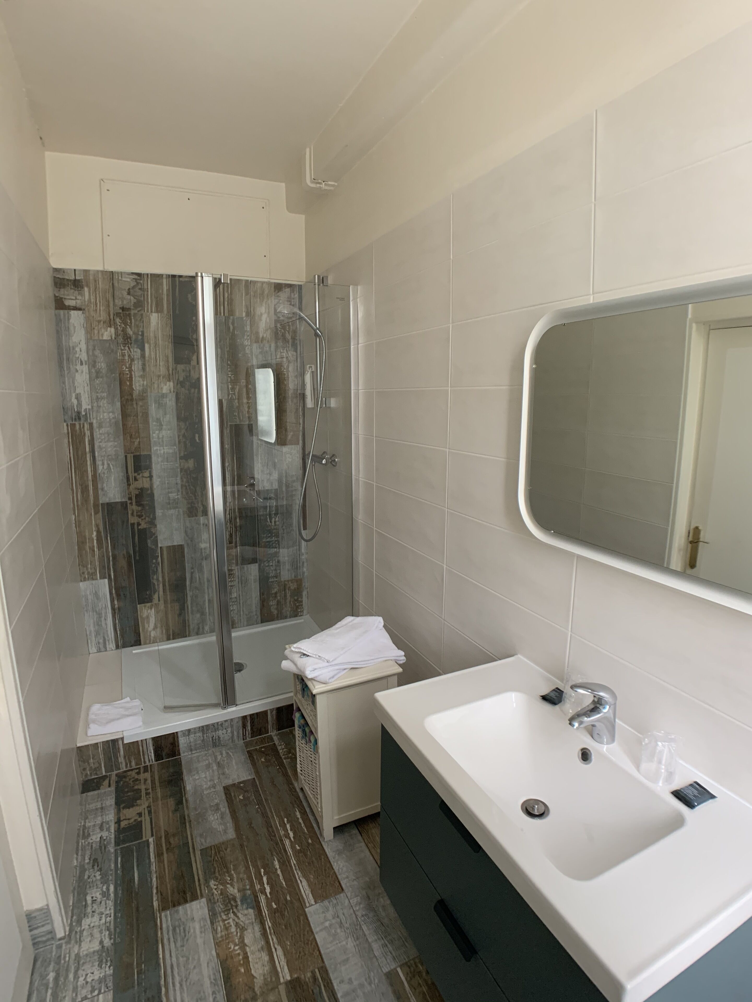 Un baño con ducha, lavamanos y espejo.