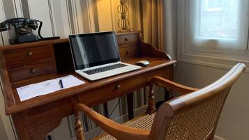 A wooden desk with a laptop, a lamp, and a telephone.