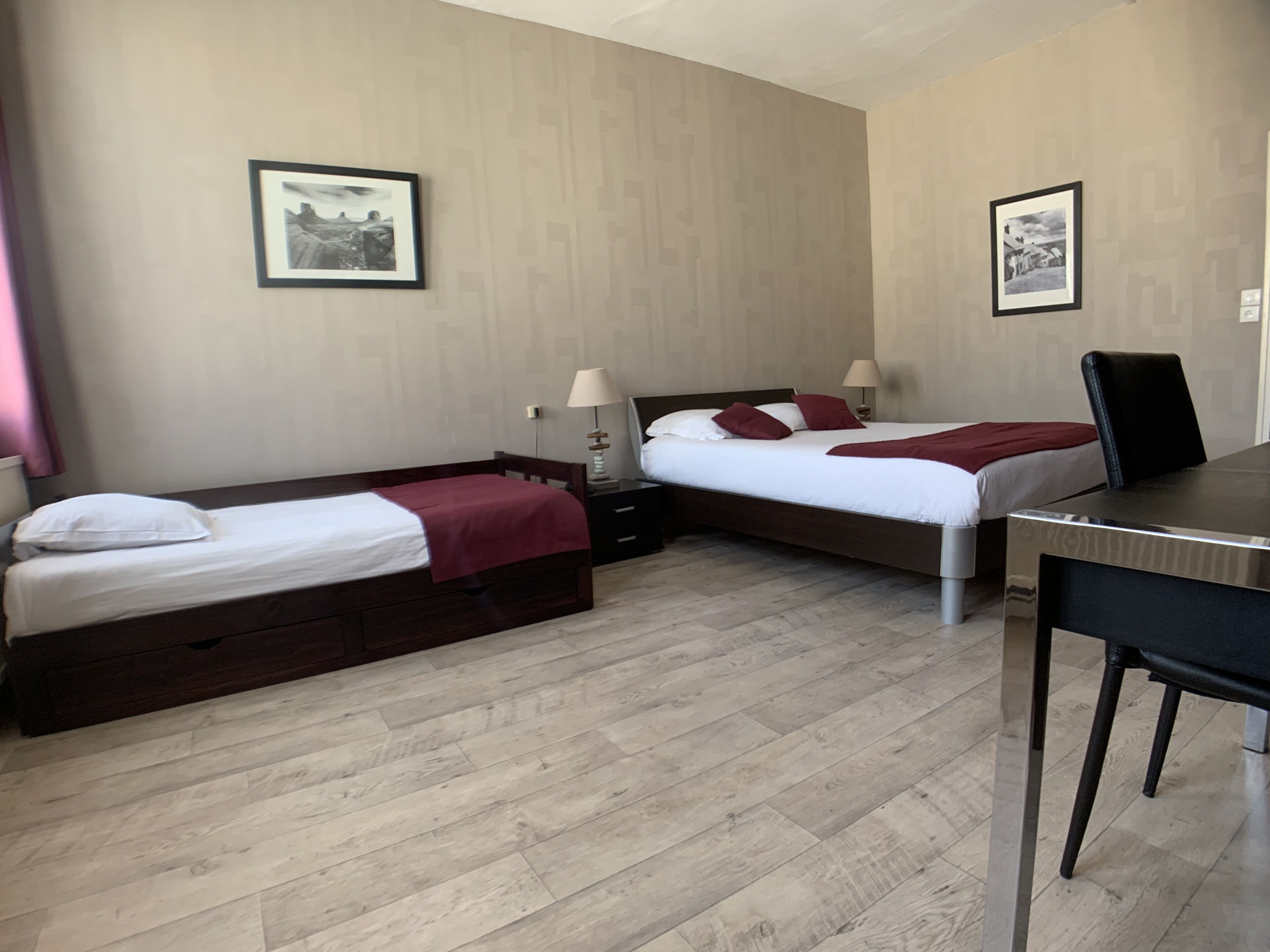 Una habitación de hotel con dos camas individuales, un escritorio y dos mesitas de noche.