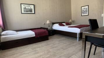 Una habitación de hotel con dos camas individuales, un escritorio y dos mesitas de noche.
