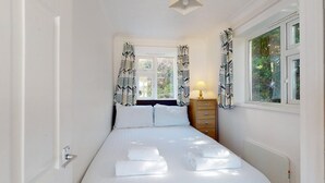 Quarto com cama, cortinas, cômoda e janela.