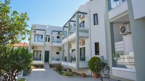 Un moderno edificio residenziale a più piani con balconi, condizionatori d'aria e un cortile centrale con piante in vaso.