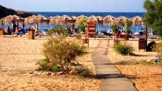 Una spiaggia con ombrelloni di paglia e un percorso che porta all'acqua.