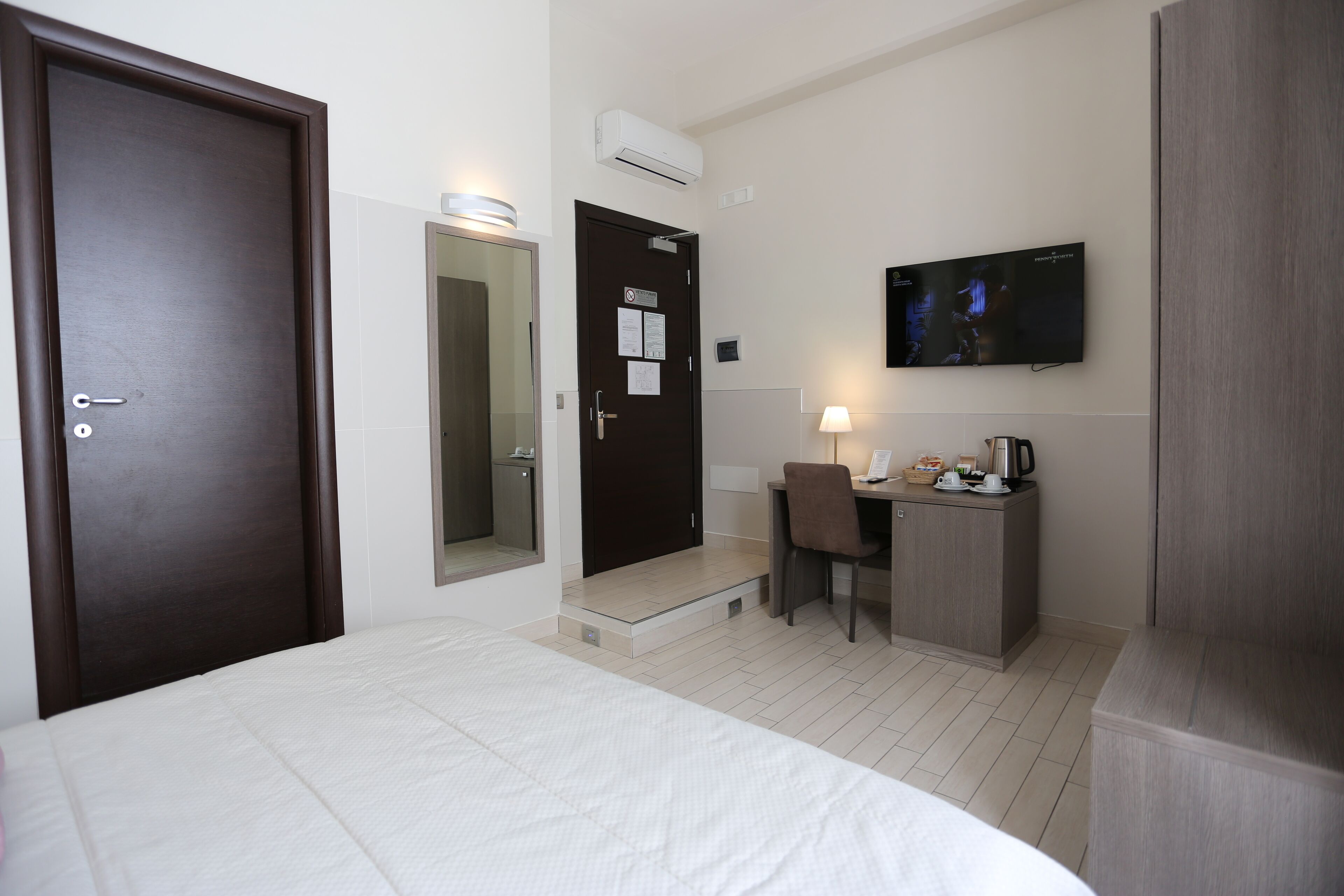 A hotel room with a bed, a desk with a chair, a TV, and a coffee maker.