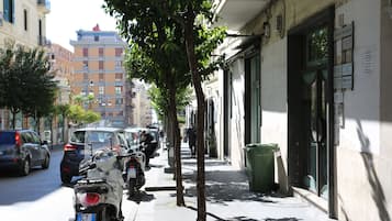 A street with parked motorcycles and cars, a sidewalk, and buildings with signage.