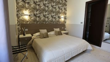 Un dormitorio con una cama grande, una mesita de noche, una silla y una pared con diseño de hojas.