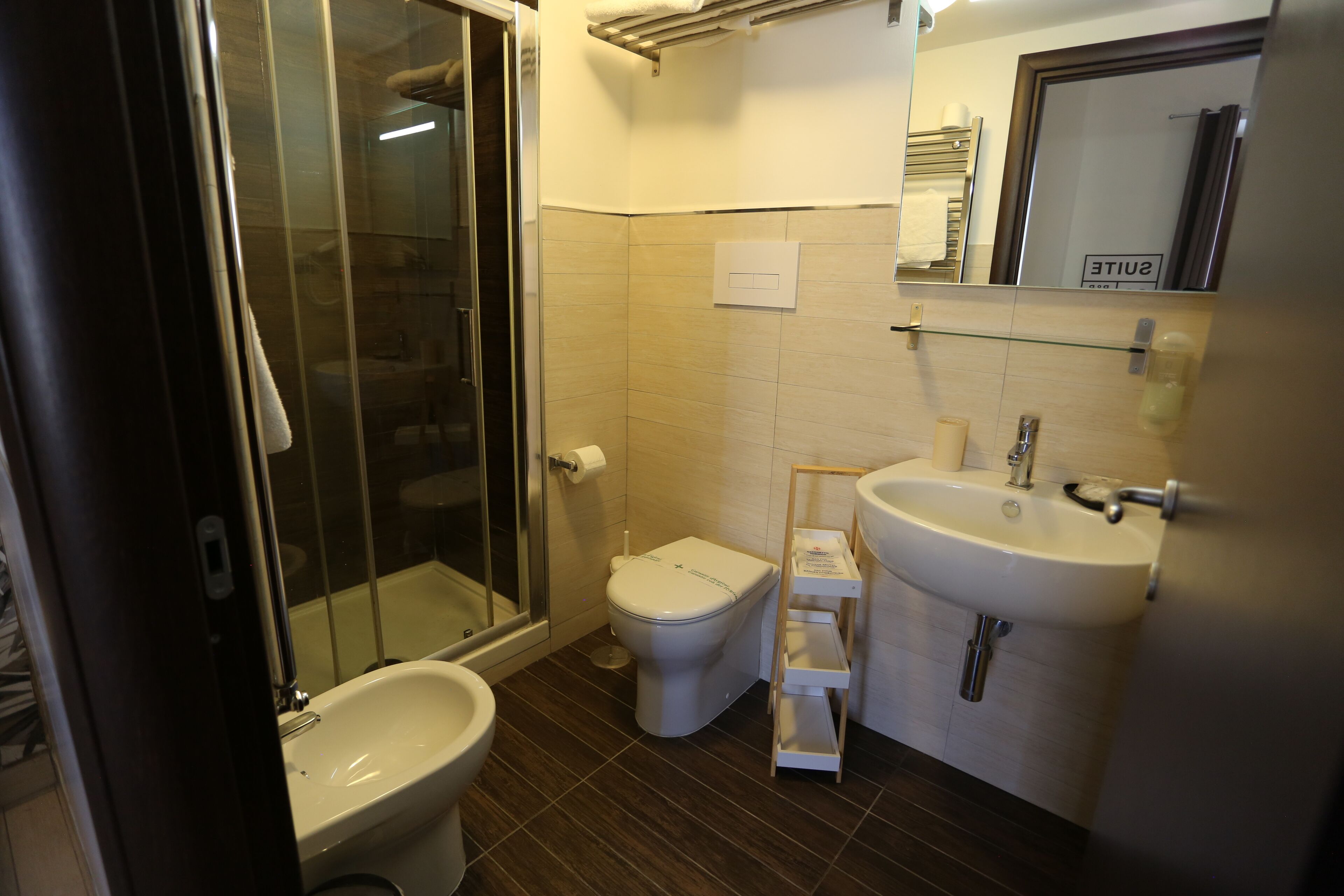 A bathroom with a glass shower enclosure, a toilet, and a sink.