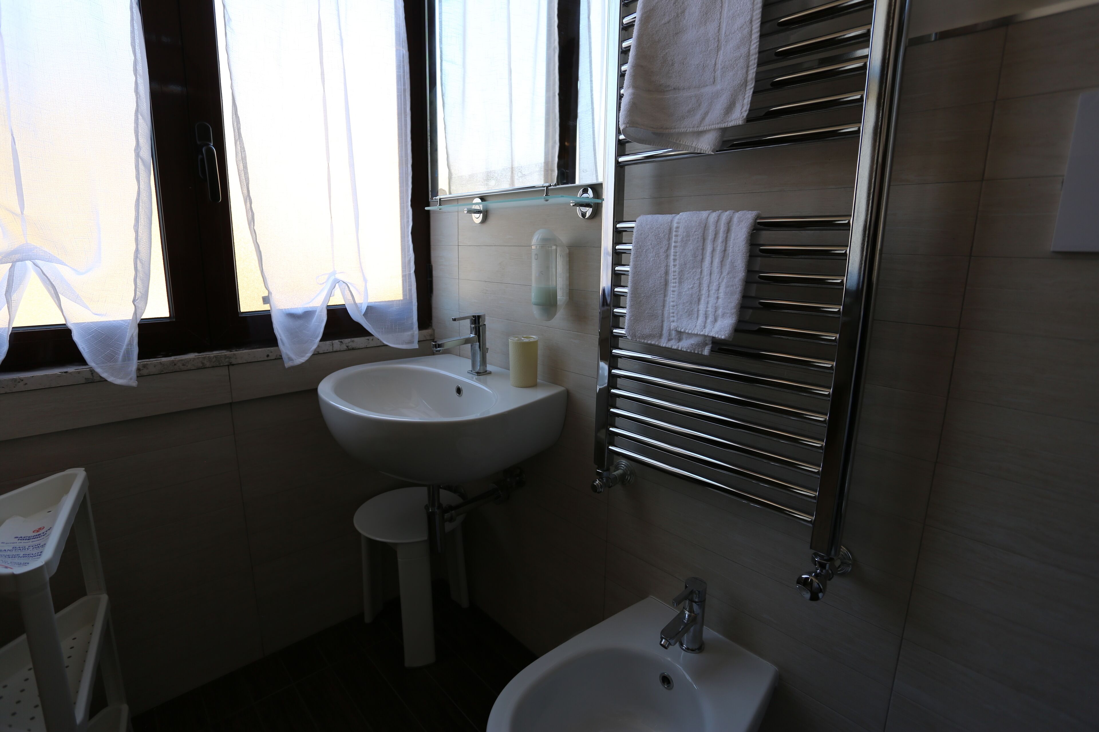 Un baño con lavamanos, espejo, toallero y bidé.