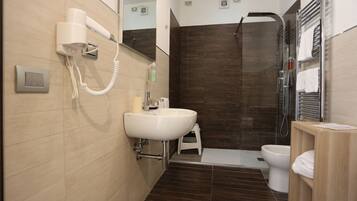 Un baño moderno con lavamanos, espejo, secador de pelo, ducha e inodoro.