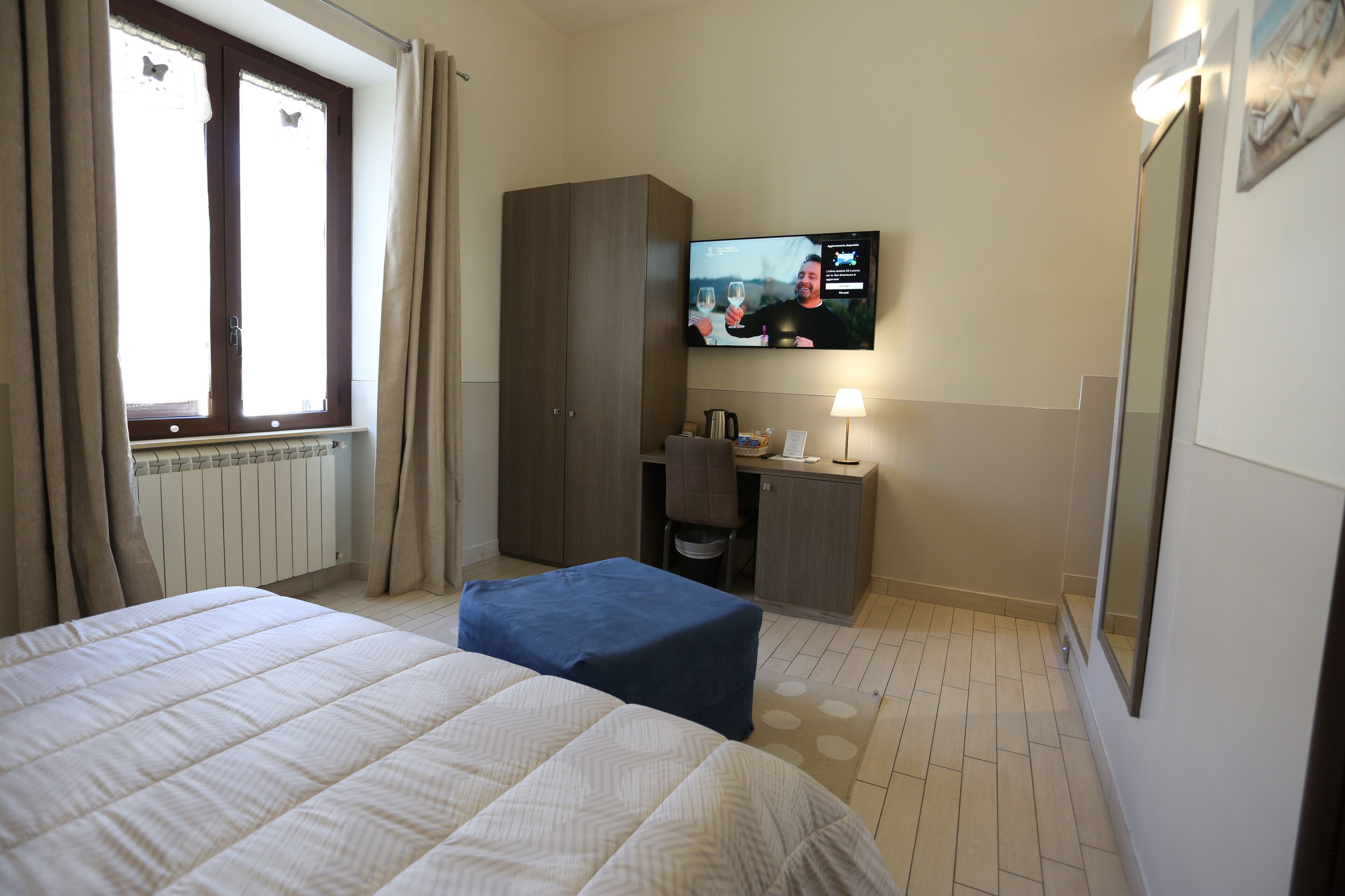 A hotel room with a bed, a desk, a television, and a wardrobe.