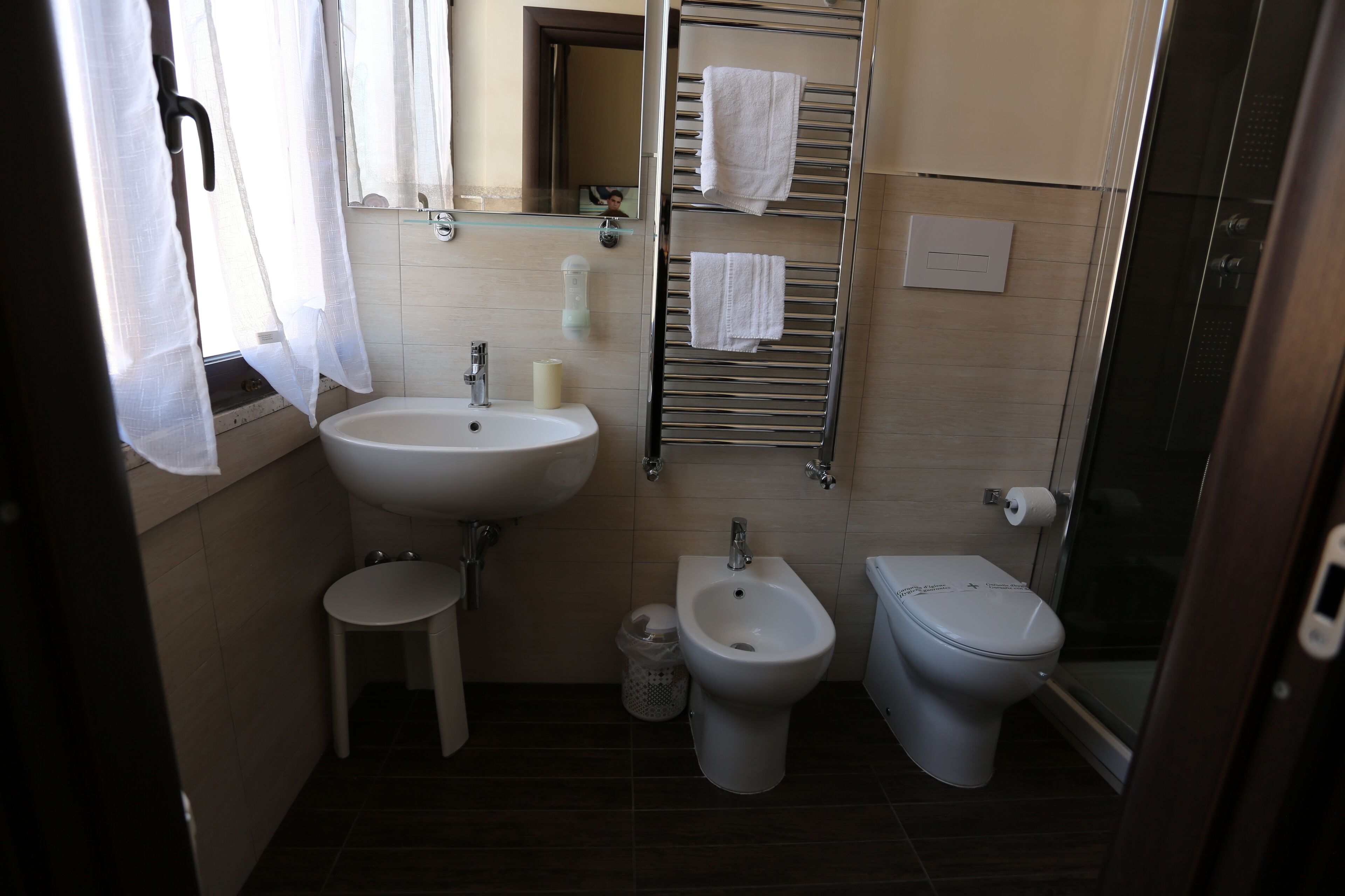 A bathroom with a sink, bidet, toilet, and a towel rack.