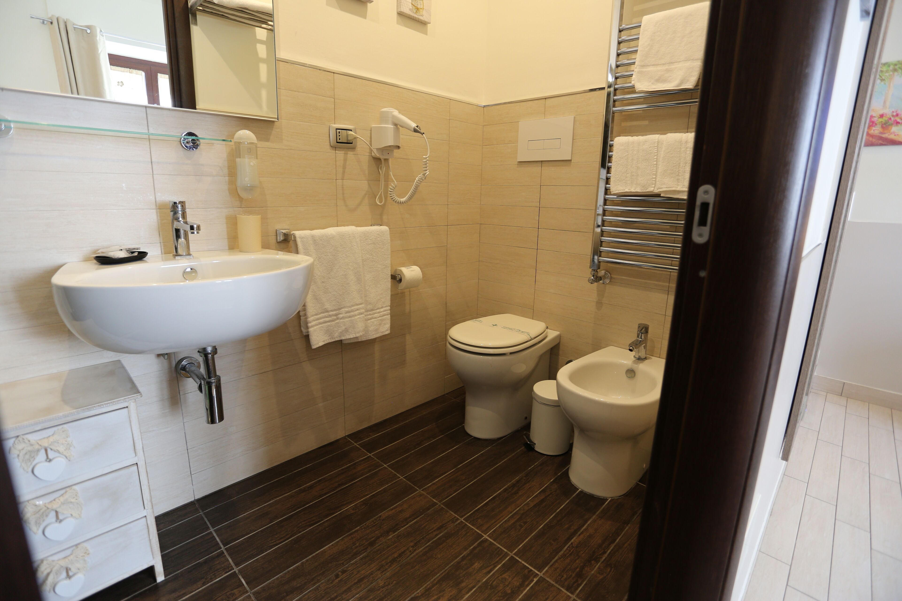 Un baño con lavabo, inodoro, bidé y un secador de pelo en la pared.