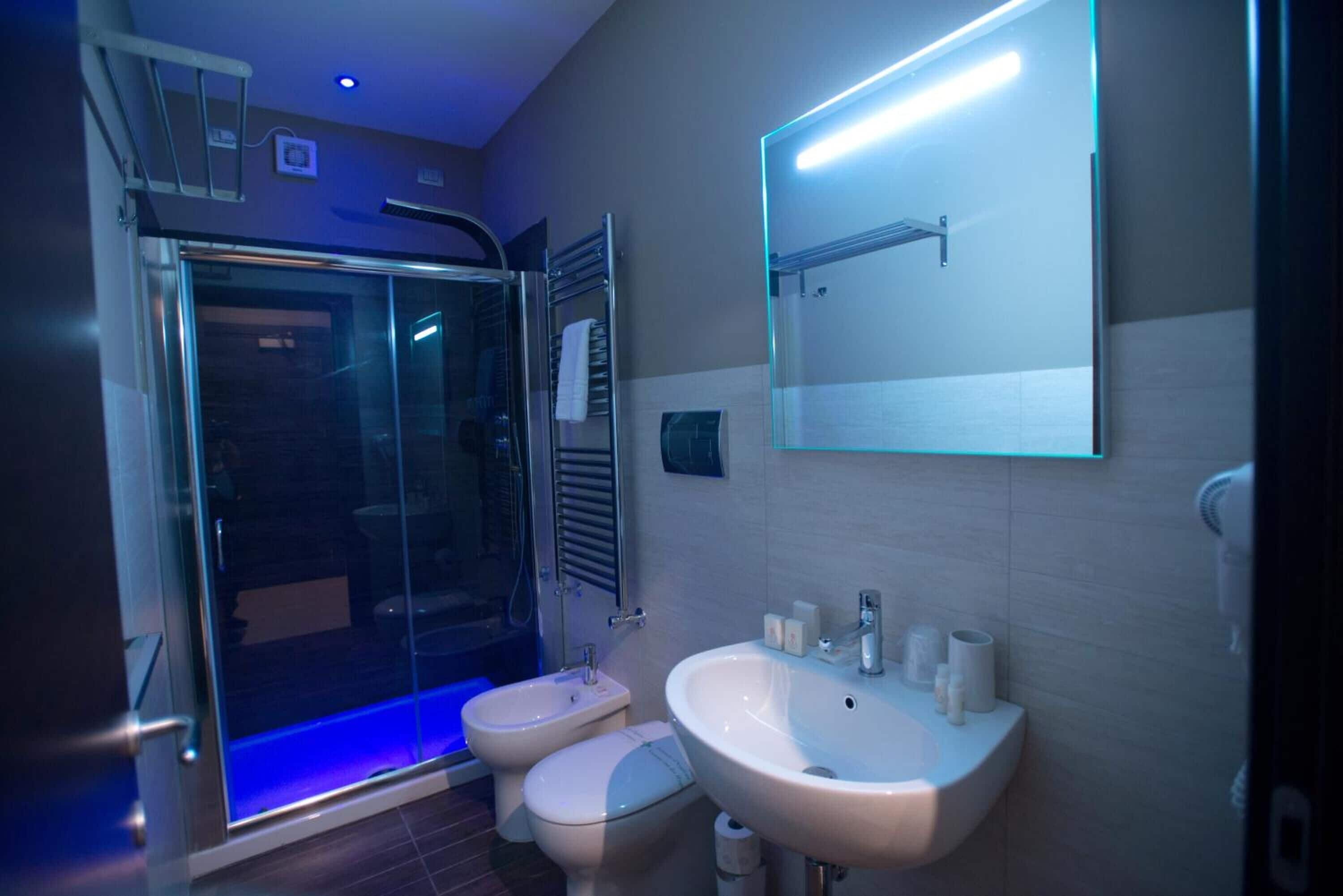 Een moderne badkamer met een glazen douchecabine, toilet en een wastafel met spiegel erboven.
