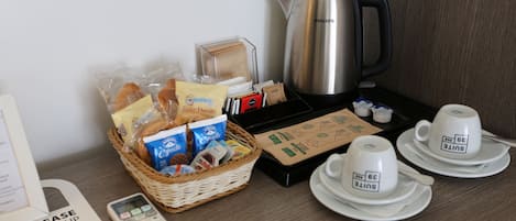 Dans une chambre d’hôtel, on trouve un plateau de petit-déjeuner comprenant une machine à café, un service à thé, des en-cas et un panier de pain.