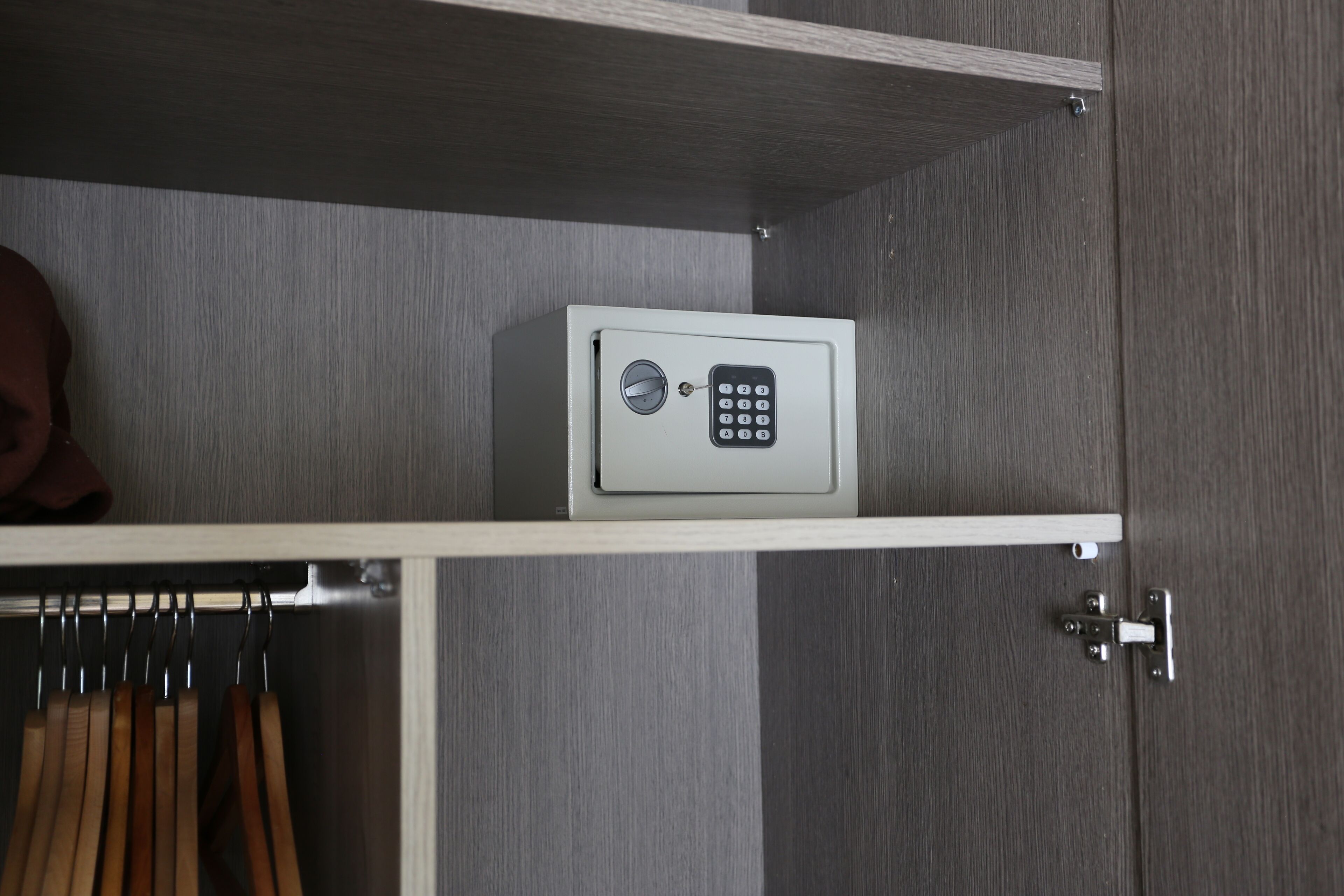 A secure safe on a shelf in a room with a wooden floor and a metal door.