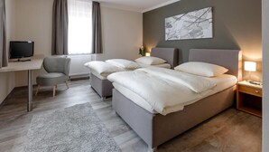 Ein Hotelzimmer mit einem großen Bett, einem Schreibtisch, einem Sessel und einem Fernseher.