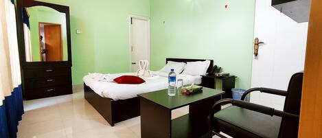 A hotel room with a bed, a desk, a chair, a mirror, and a wardrobe.