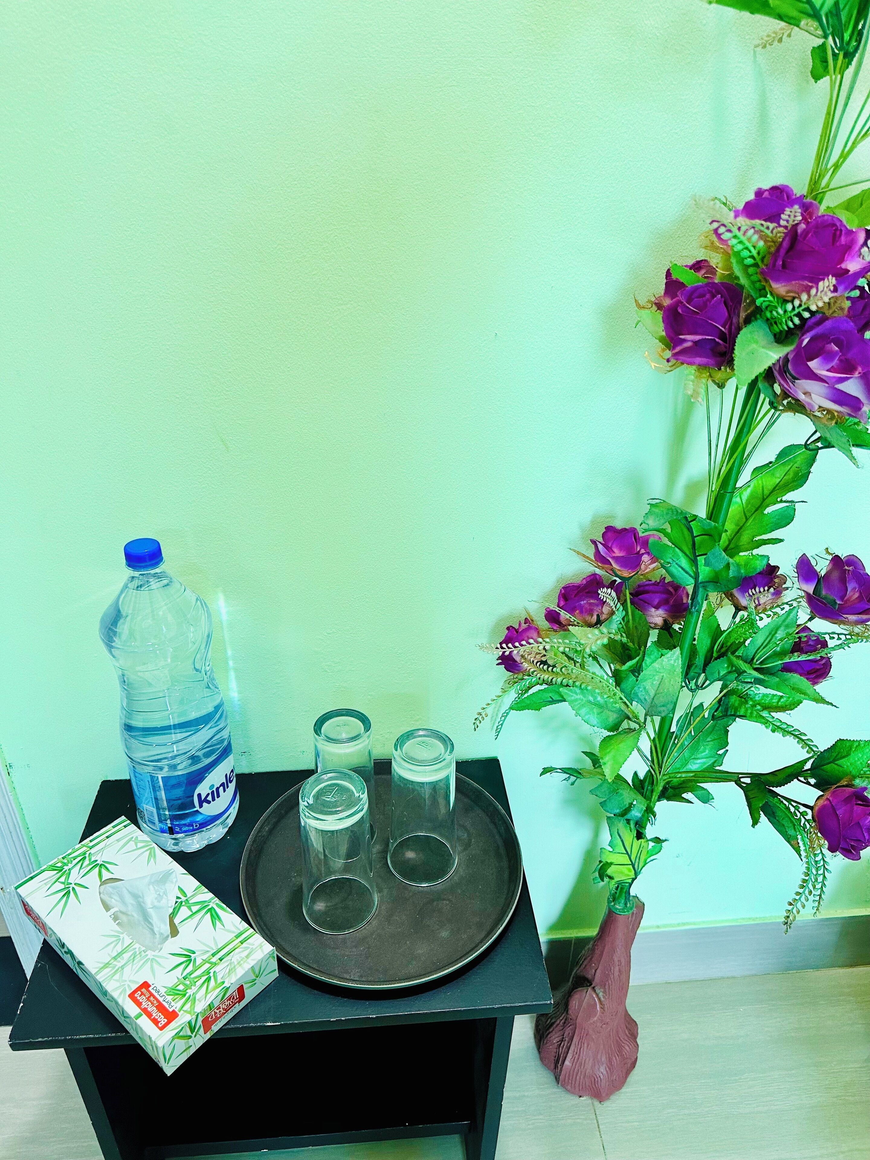 A table with a water bottle, glasses, and a tissue box.