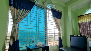 Ein Zimmer mit zwei schwarzen Sofas, einem kleinen Tisch mit einer Flasche und Gläsern sowie einem Fenster mit blauen Vorhängen.