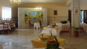 A dining area with tables set for a meal, a mural on the wall, and a chandelier. - Grandinetti Hotel (Parenti)