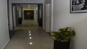 Un pasillo con suelo de baldosas, cuadros en las paredes y plantas en macetas.