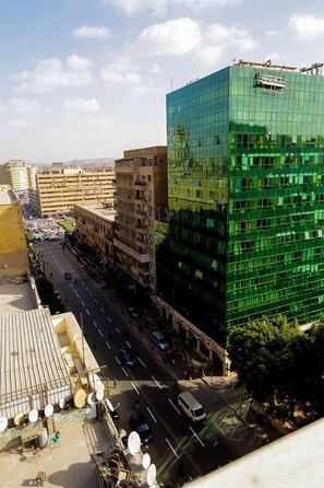 A multi-story building with a modern glass facade, adjacent to a busy street with vehicles and pedestrians. - Azar Boutique Hotel (Cairo)