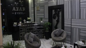 Un moderno vestíbulo de hotel con mostrador de recepción, paredes con diseño y zonas de estar.