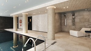 A modern indoor pool area with a clear pool, a lounge chair, and a shower area. - Urban Valley Resort (San Gwann)