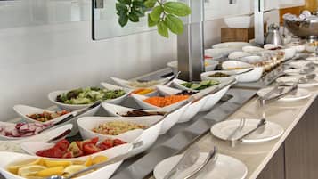 Un bufé con diversas opciones de comida, incluyendo ensaladas, frutas y verduras.