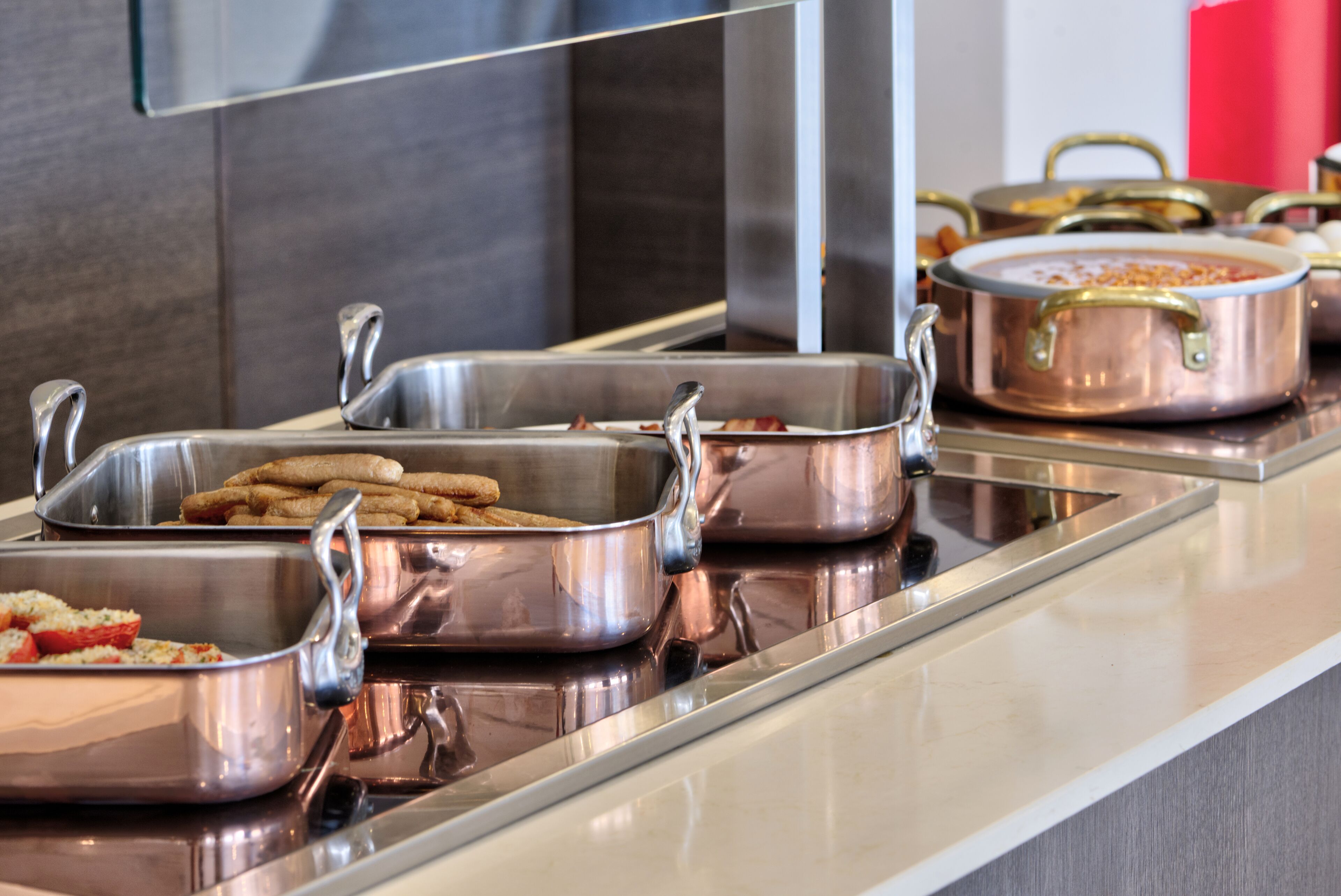 Montaje tipo buffet con diferentes alimentos en recipientes de metal.