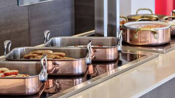 Montaje tipo buffet con diferentes alimentos en recipientes de metal.