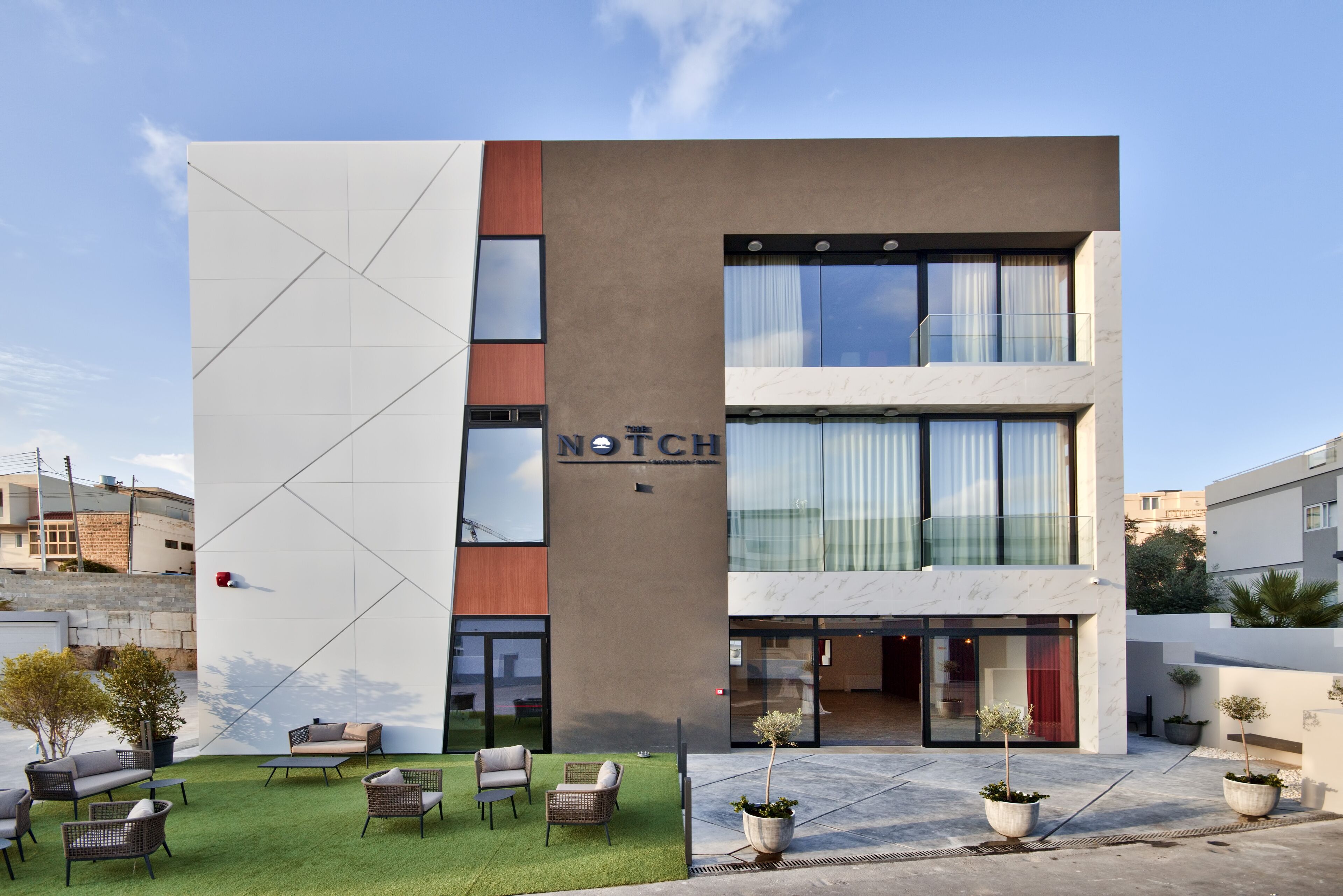 A modern hotel with a geometric facade, outdoor seating, and a well-maintained courtyard.