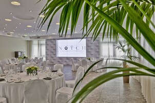 A conference room with round tables, white chairs, and a projection screen displaying "The Notch".