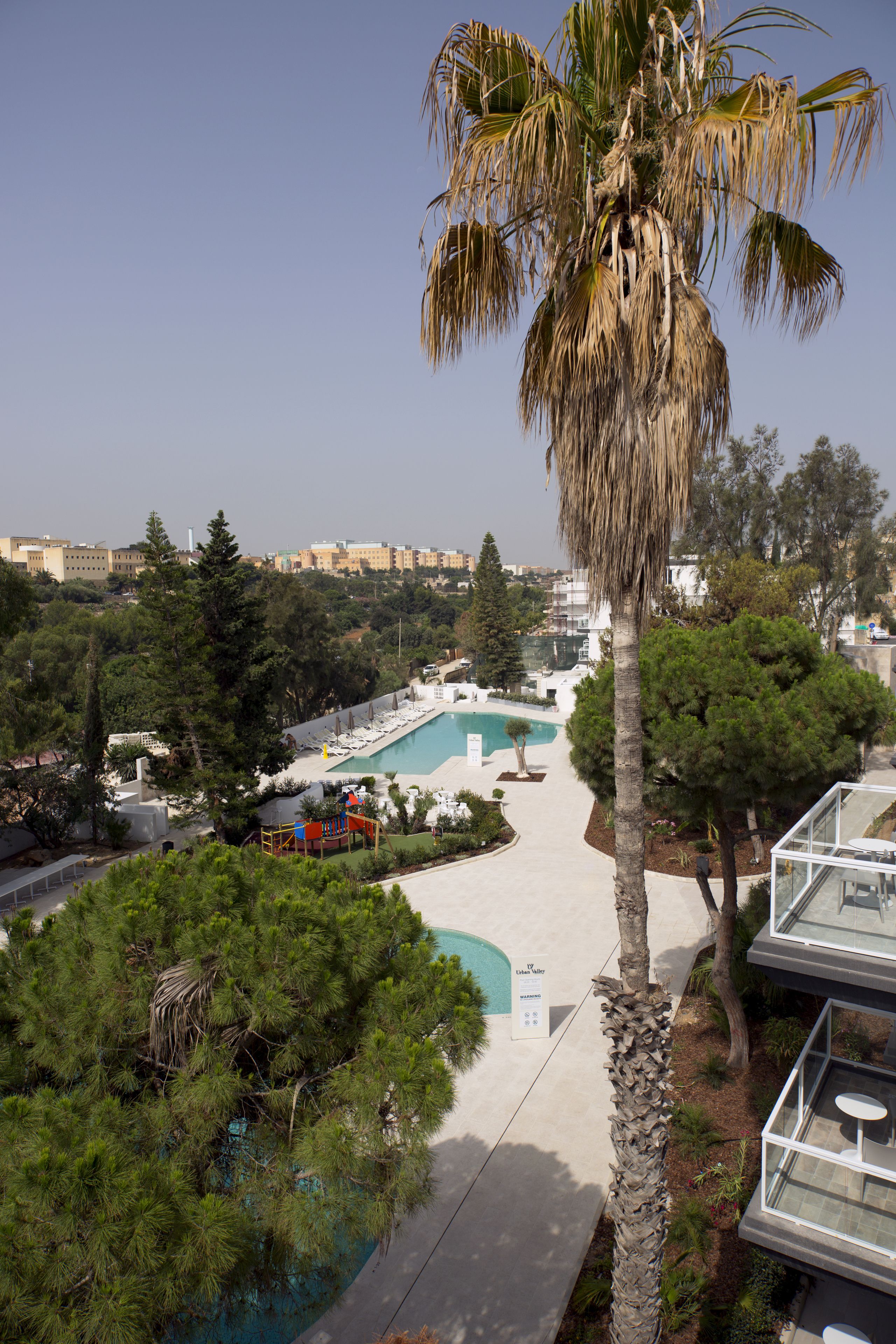 A resort with a swimming pool, palm trees, and a view of the city.
