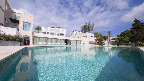 A modern pool area with clear water, surrounded by contemporary buildings and a clear sky. - Urban Valley Resort (San Gwann)