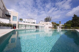 A modern pool area with clear water, surrounded by contemporary buildings and a clear sky.