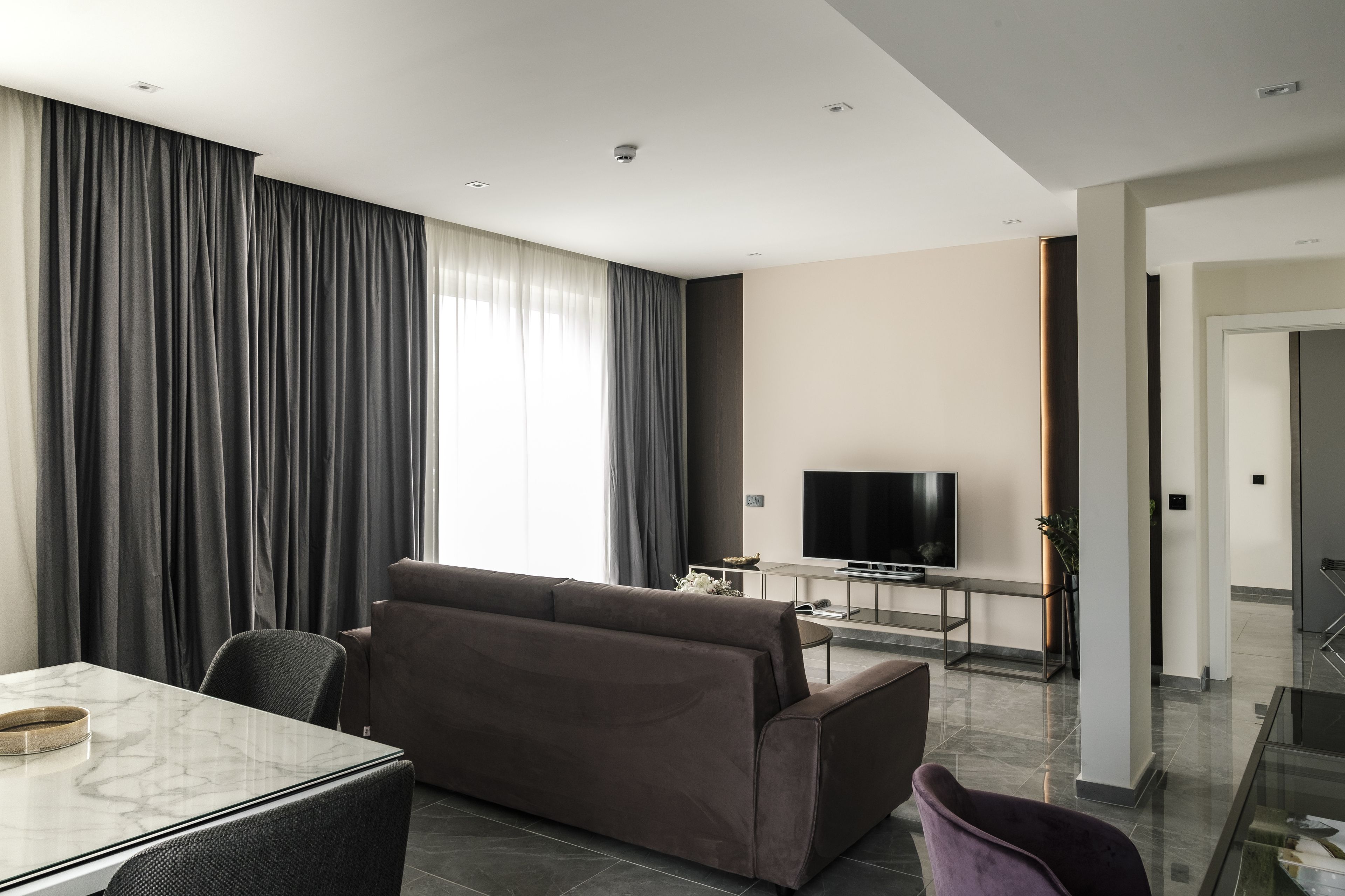 Uma sala de estar moderna com um sofá, uma mesa de jantar e uma televisão.