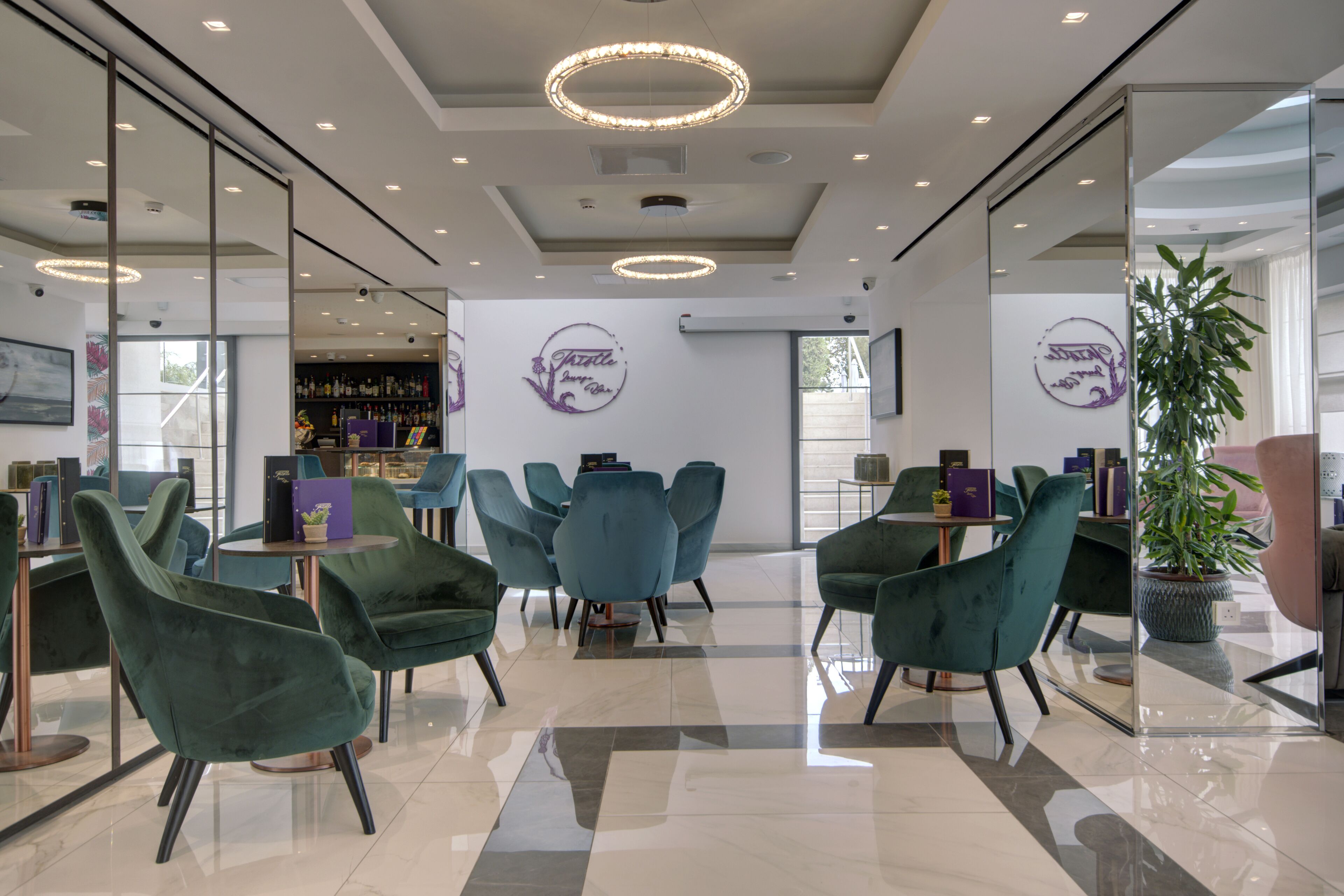 A modern interior with teal chairs, a bar area, and a large potted plant.