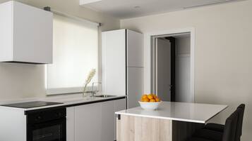 Una cocina moderna con horno empotrado, un lavabo y una encimera blanca.