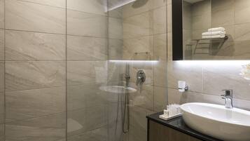 Une salle de bain moderne avec une douche à parois de verre, un grand lavabo et un miroir au-dessus du lavabo.