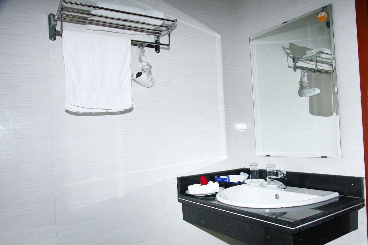 A bathroom with a white sink, a mirror, and a towel hanging on a rack.