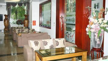 Eine Hotelhalle mit Sofas, einem Glastisch und einer großen Vase mit Blumen.