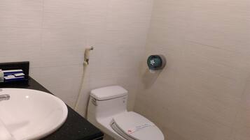 Une salle de bain avec un lavabo blanc, des toilettes et un sèche-mains fixé au mur.