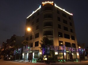 A hotel with a modern design, featuring a prominent 'Hotel' sign at the top. The building has multiple floors with balconies, and the entrance is adorned with colorful lights. - Golden Thai Binh Hotel (Thai Binh)