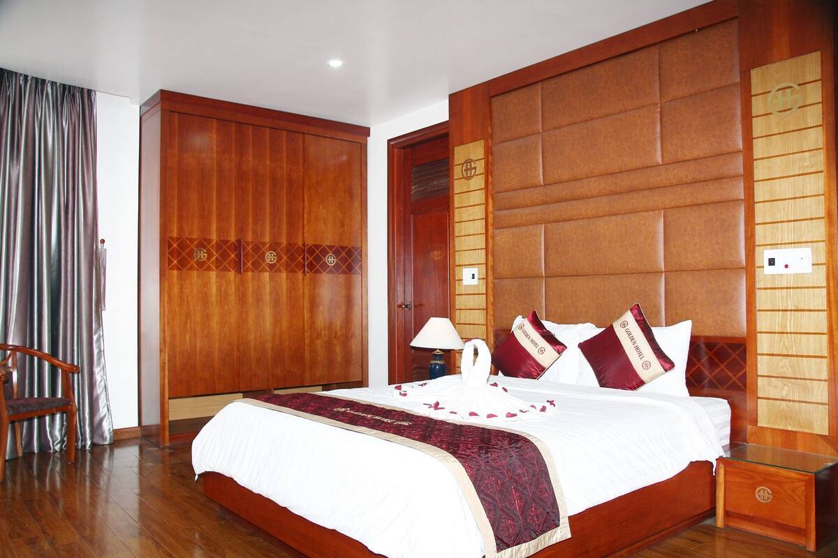 A hotel room with a wooden bed, a nightstand, a chair, and a wardrobe.