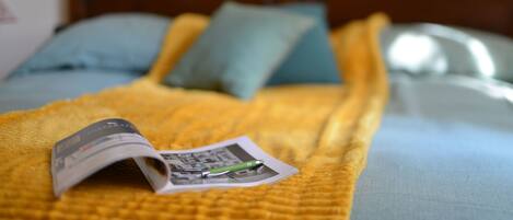 A bed with a yellow blanket, a magazine, and a pen on it.